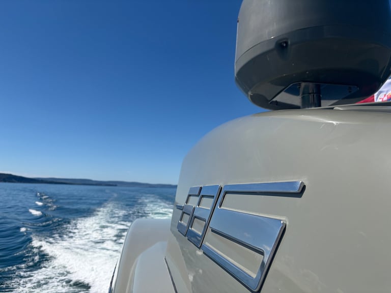 White boat on blue water with clear sky, showing side railing and wake behind vessel